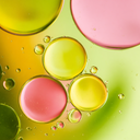 Colorful bubbles on a liquid surface with pink, yellow, and green hues.