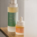 Two YINA skincare products on a wooden surface with a neutral background