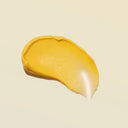 A textured smear of golden yellow YINA Recovery body treatment cream on a solid pale beige background.